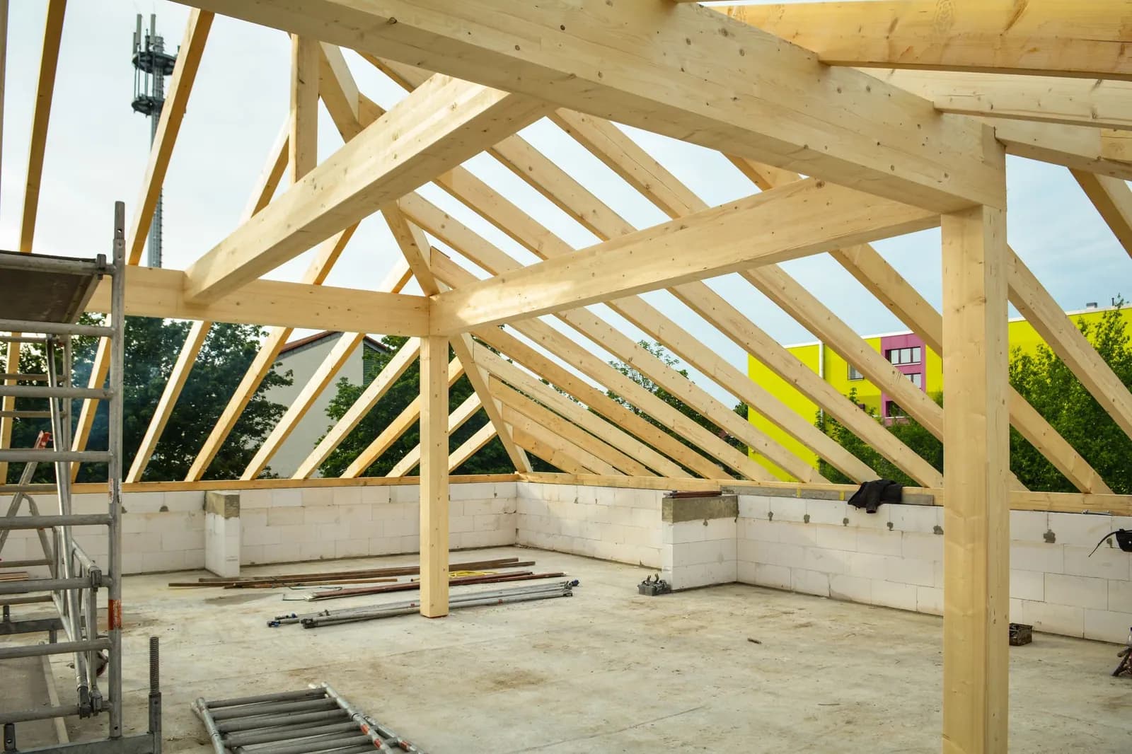 Hölzerner Dachstuhl im Bau auf einem Rohbau aus Beton vor blauem Himmel