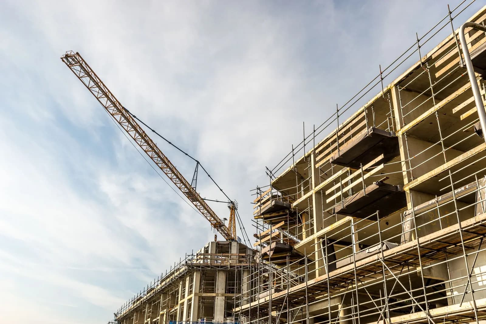 Baukran über einer Baustelle mit Gerüst bei Sonnenschein