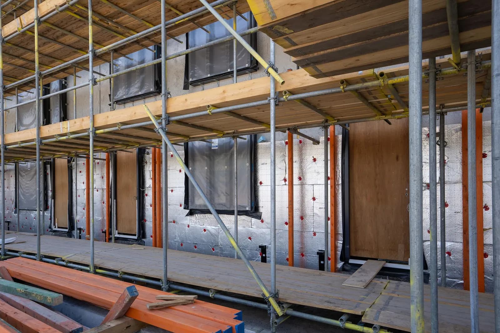 Gerüst vor einer Hausfassade mit Dämmplatten und neu eingebauten Fenstern