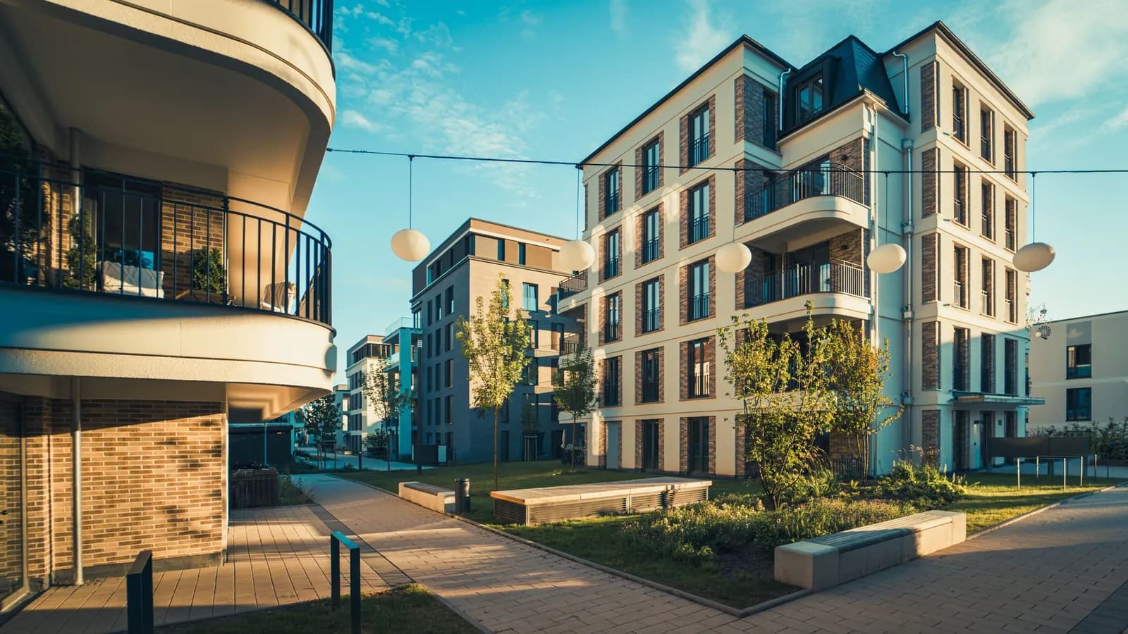 Modernes Mehrfamilienhaus mit offenen Balkonen und heller Fassade bei Tageslicht